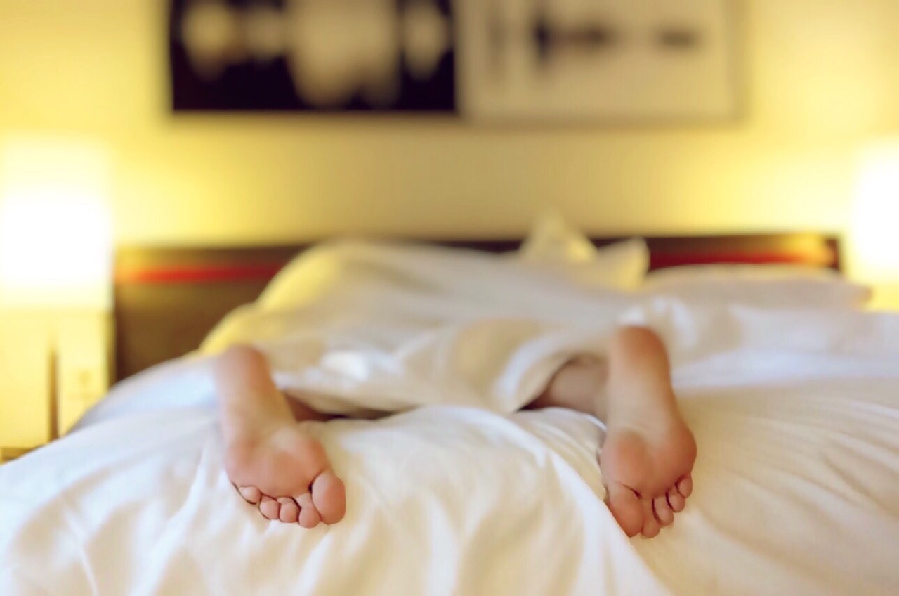 Person sover i seng med fødderne ude